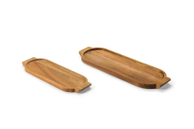 A curated flat-lay of four elegant serving trays—walnut wood, white ceramic, brushed brass, and black marble—arranged on a linen tablecloth with fresh lemons and eucalyptus sprigs.